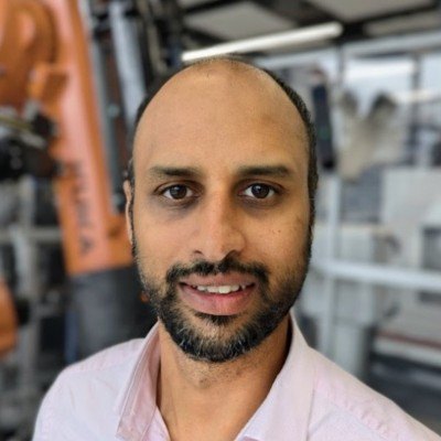 Dr Mayank ('Rocky') Verma — Chief Engineering Officer at Kaipability Ltd, photographed beside an industrial robot arm.