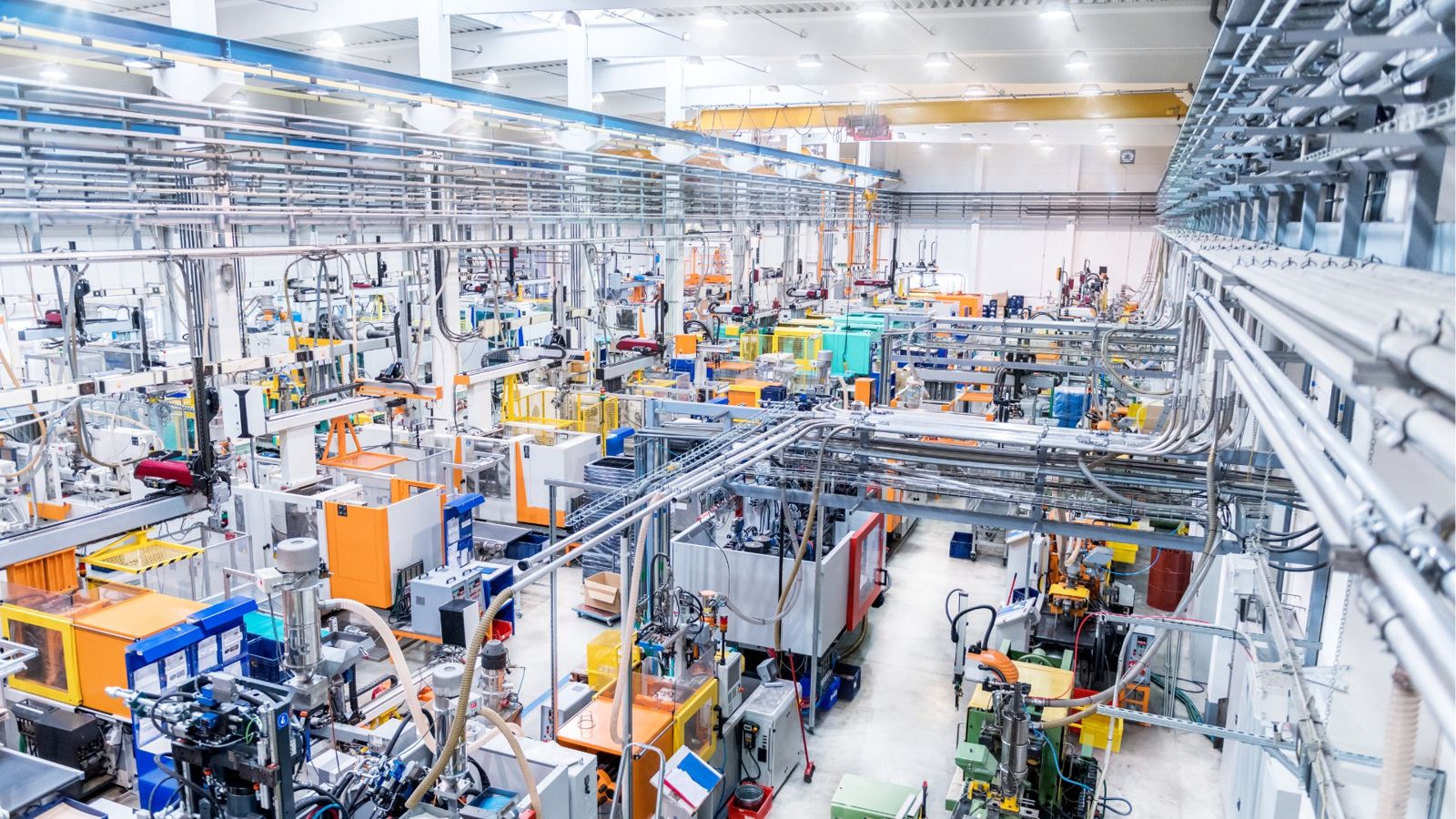 Aerial view of a vast injection-moulding production hall, rows of moulding cells in colour beneath an overhead crane gantry