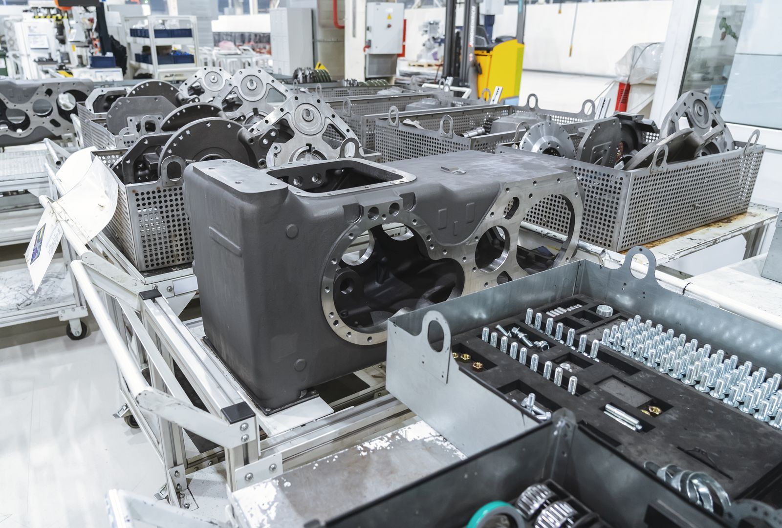 Engine block castings stacked in metal baskets on factory trolleys, ready for assembly — manufacturing output as stock-keeping units, the literal product on the shelves.