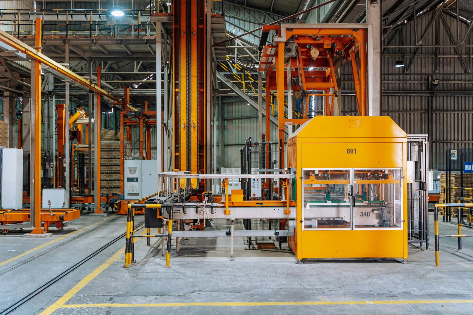 A modern factory bay with large orange industrial automation cells in coordinated layout