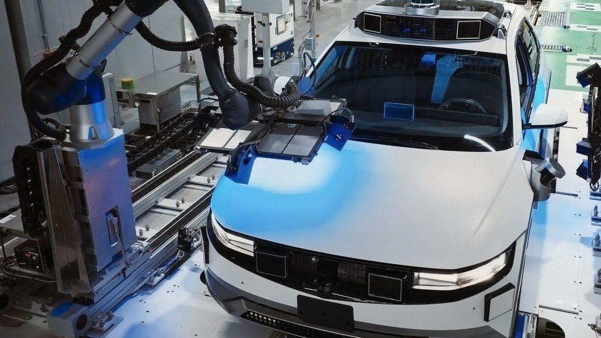 Automated visual-inspection station on a car assembly line, white SUV body under a blue structured-light vision-AI gantry with metrology arms, factory floor