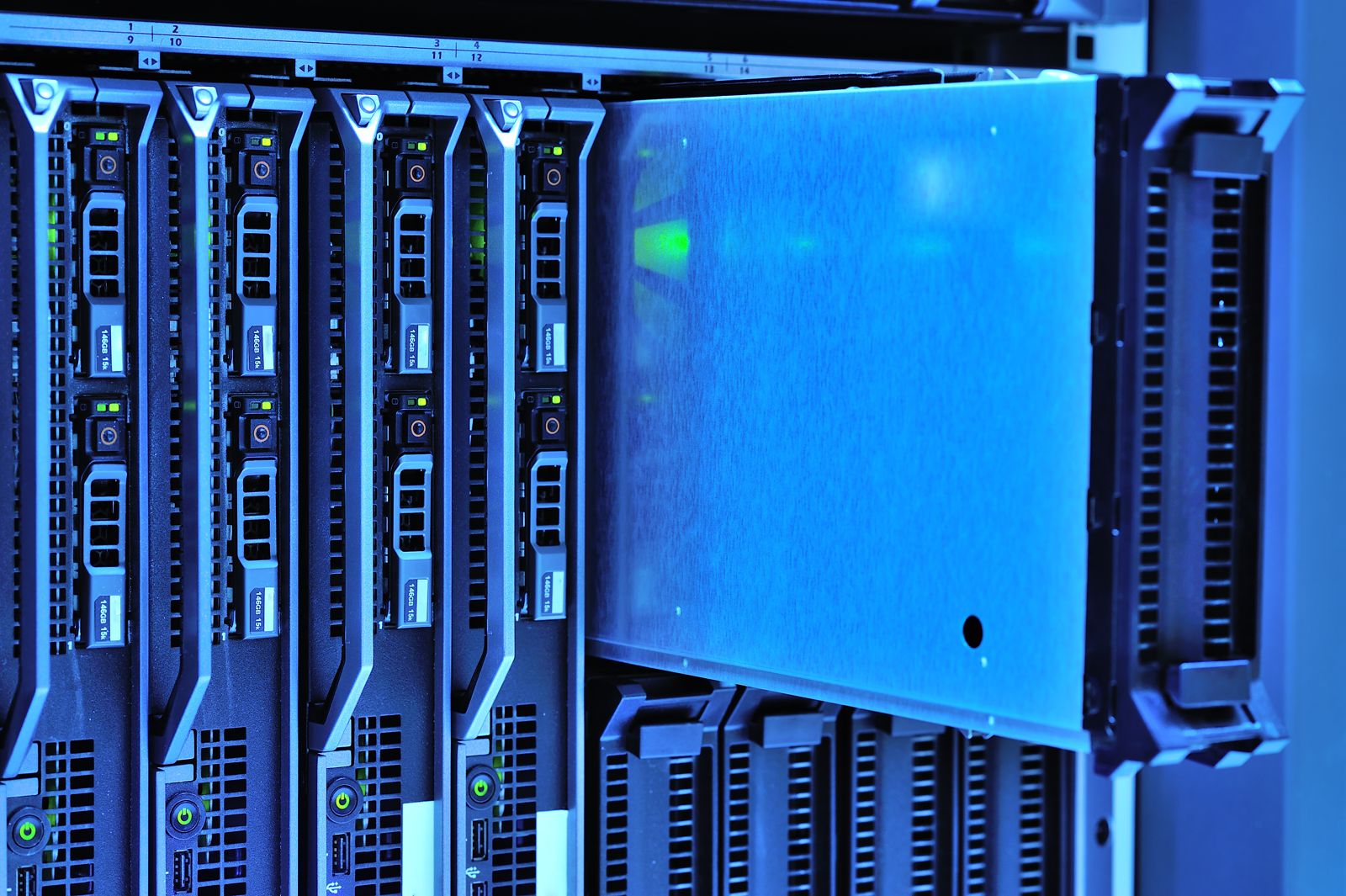 Blade servers half-drawn from a rack under blue light, green status LEDs along the row
